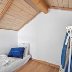 Ein Schlafzimmer mit Dachschrägen, Holzboden und einem Bett mit Kissen.