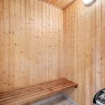 Sauna mit Holzwand und Sitzbank sowie Steinbehälter