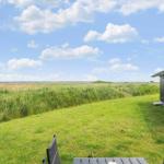 Grünes Grasfeld mit Blick auf Horizont. Holzhaus mit Tisch und Stühlen.