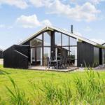 Moderne Holzhütte mit großem Glasbereich und Terrasse im Grünen.
