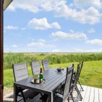 Terrasse mit Tisch und Stühlen bietet Blick auf Grasland und Himmel.