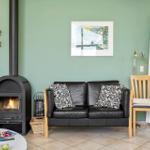 Ein Wohnzimmer mit Sofa, Kamin und Glastür. Wandfarbe ist grün.