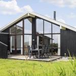 Modernes Holzhaus mit großem Glasbereich und Terrasse mit Esstisch.