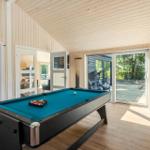 Room with pool table, wood walls, and glass door to outdoor area.