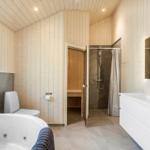 Bathroom with whirlpool, shower, and sauna. Wooden walls and white sink.