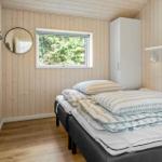 Bedroom with wooden walls, bed, and window to the forest.