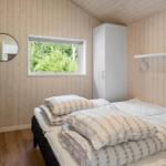 Bedroom with wooden walls, bed, window, and wardrobe.