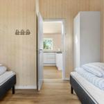 Two beds in a room with wooden walls and door to bathroom.