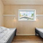 Two single beds in a room with wooden walls and a window.