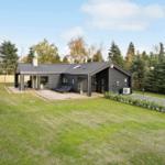 Modern villa with terrace, garden, and forest in the background.