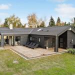 Modern villa with wooden terrace, sun loungers, and garden.