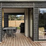 Deck with table, chairs, and grill. Wooden floor and large windows.