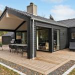House with terrace, grill, and loungers. Wooden deck and black wood cladding.