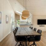 Large dining area with wooden table and chairs, kitchen area and TV wall.