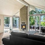 Living room with fireplace, sofa, and TV. Large windows with garden view.