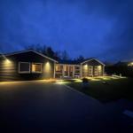Modernes Haus mit beleuchteter Fassade und Terrasse bei Nacht.