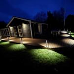 Hütte mit beleuchteter Terrasse und Grünfläche bei Nacht.