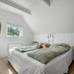 Schlafzimmer mit Bett, Fenster und weißen Wänden.