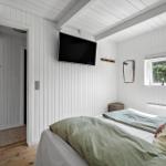 Schlafzimmer mit Bett, TV und Fenster mit Blick auf Grün.