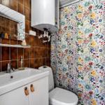 Badezimmer mit Waschbecken, Toilette und blumigem Duschvorhang.