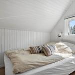 Schlafzimmer mit Bett, Fenster und weißen Wänden.