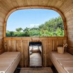 Holzsauna mit Sitzbänken und großem Bogenfenster zur grünen Außenaussicht.