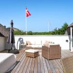 Terrasse mit Liege, Sitzgruppe und dänischer Flagge. Holzdecke und Strohdach.