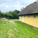 Gelbes Haus mit Strohdach und grünem Garten