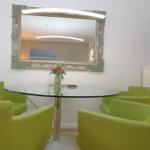 Runder Tisch mit grünen Stühlen, Spiegel und Blumen.