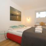 Schlafzimmer mit Bett, Wandbild und Fenster mit Jalousie.