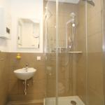 Badezimmer mit Dusche, Waschbecken und Spiegel