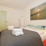 Schlafzimmer mit Bett, Kissen und Wandbild. Handtücher auf dem Bett.