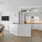 Küche mit Essbereich und Fernseher. Weiße Arbeitsplatten und Schränke.