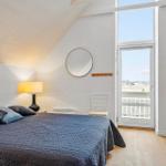 Schlafzimmer mit Dachschräge, Bett, Lampe, Spiegel und Balkontür.