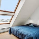Schlafzimmer mit Dachfenster und blauer Bettdecke.