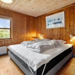 Bedroom with wooden walls, bed, and window view of trees