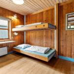 Room with two mattresses, wooden walls, and window.