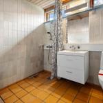 Bathroom with shower, sink and toilet. Tile floor and walls.