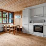 Kitchen with dining area, wooden ceiling and windows. White cabinets and wooden furniture.