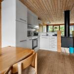 Kitchen with wooden walls, white built-in appliances, and wood stove