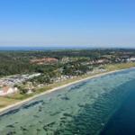 Aerial view of a coastal landscape with beach, campsite, and forest
