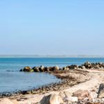Strand mit Steinen und ruhigem Meer im Hintergrund