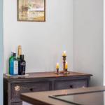 Wooden cabinet with bottles and lit candles. Wall picture above the cabinet.