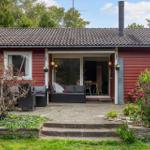 Red wooden house with terrace and garden. Glass door leads inside.