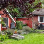 Red wooden house with garden and terrace with seating.