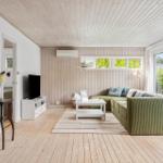 Living room with green sofa, wooden floor, and large windows.