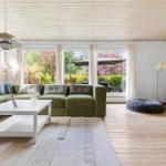 Living room with green sofa, fireplace, and large window to outdoor terrace.