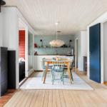 Kitchen with dining table, wooden floor, and wood-burning stove in living area.
