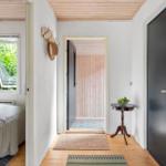 Hallway with wooden floor, door, and view into bedroom with window.
