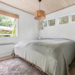 Bedroom with bed, windows, and wooden ceiling.